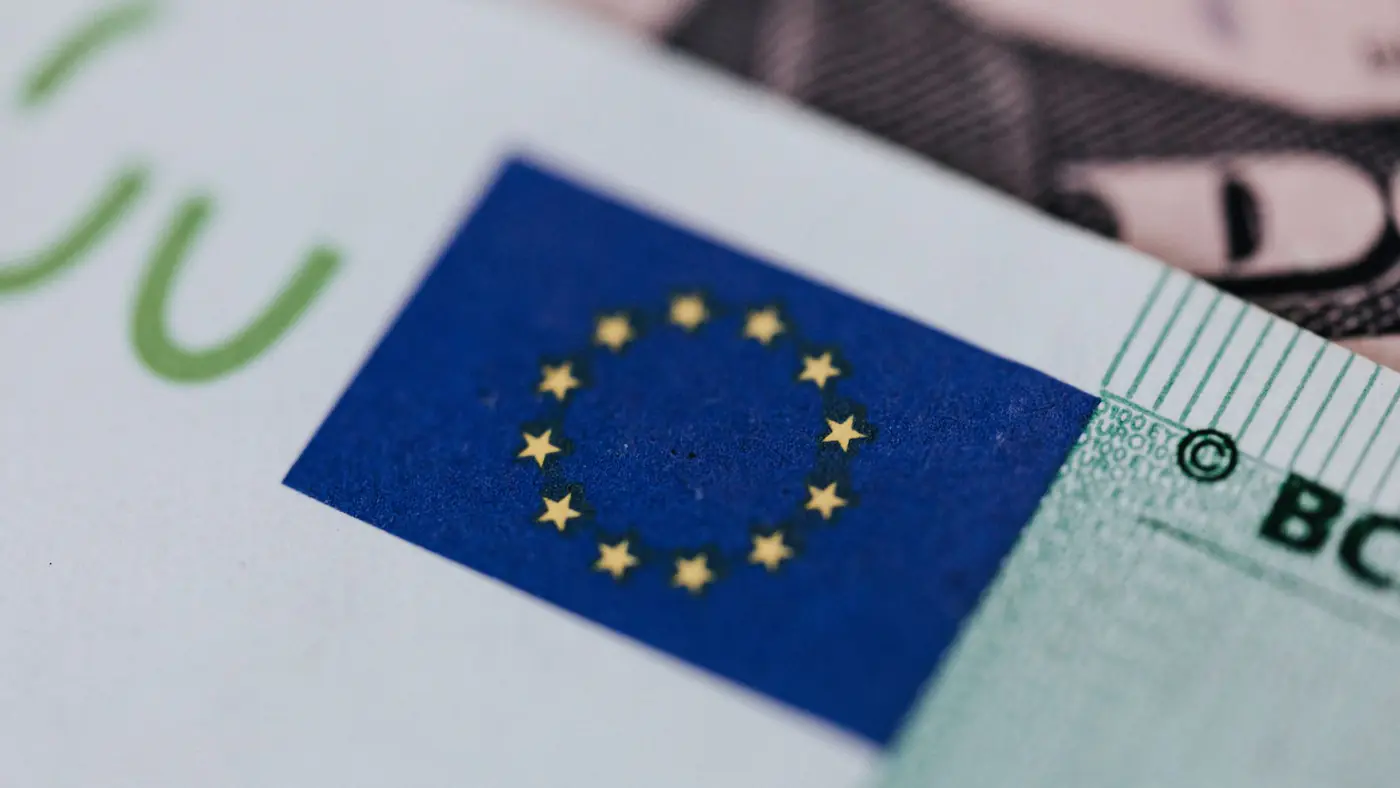 From above of crop banknote of European Union placed on table with dollars