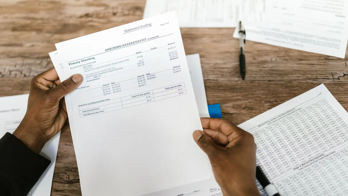 Hands holding financial papers for tax preparation and analysis.