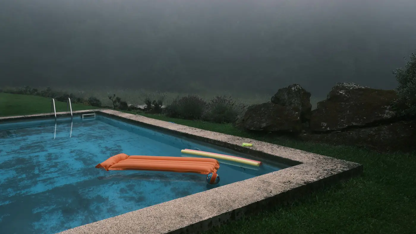A serene outdoor pool surrounded by fog and lush greenery at dawn. Perfect for leisure and relaxation themes.