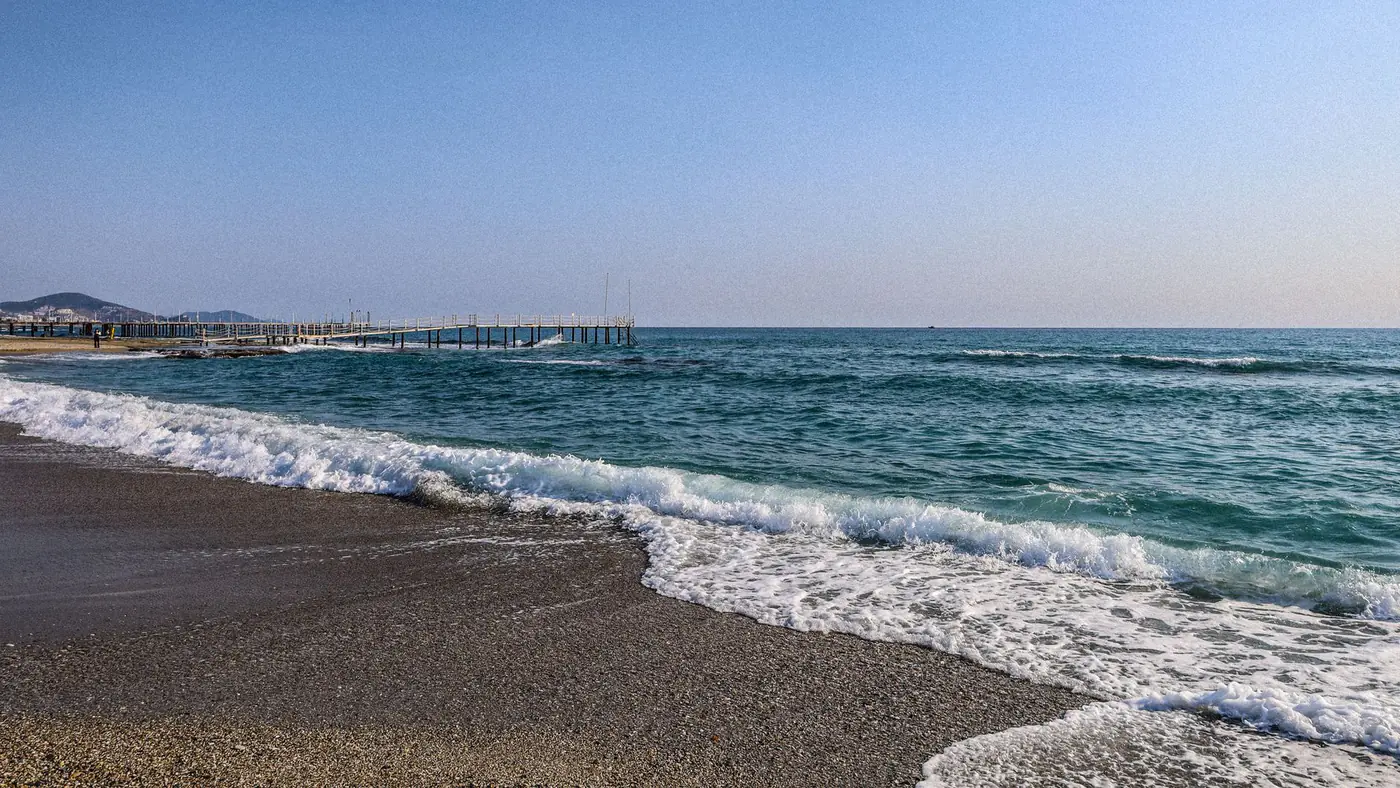 Peaceful beach scenery in Alanya, Turkey with gentle waves and clear skies.
