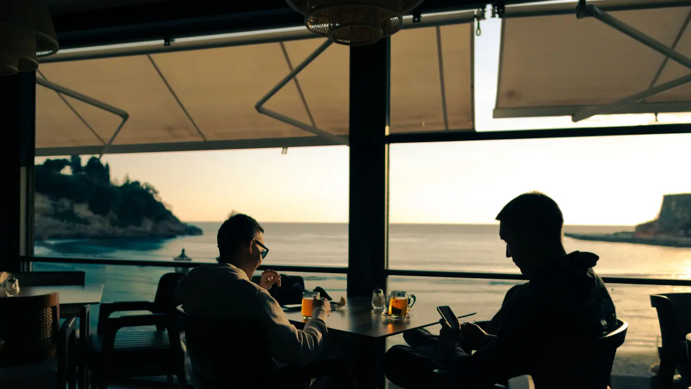 Relaxing ocean view with people dining indoors at sunset in Montenegro.