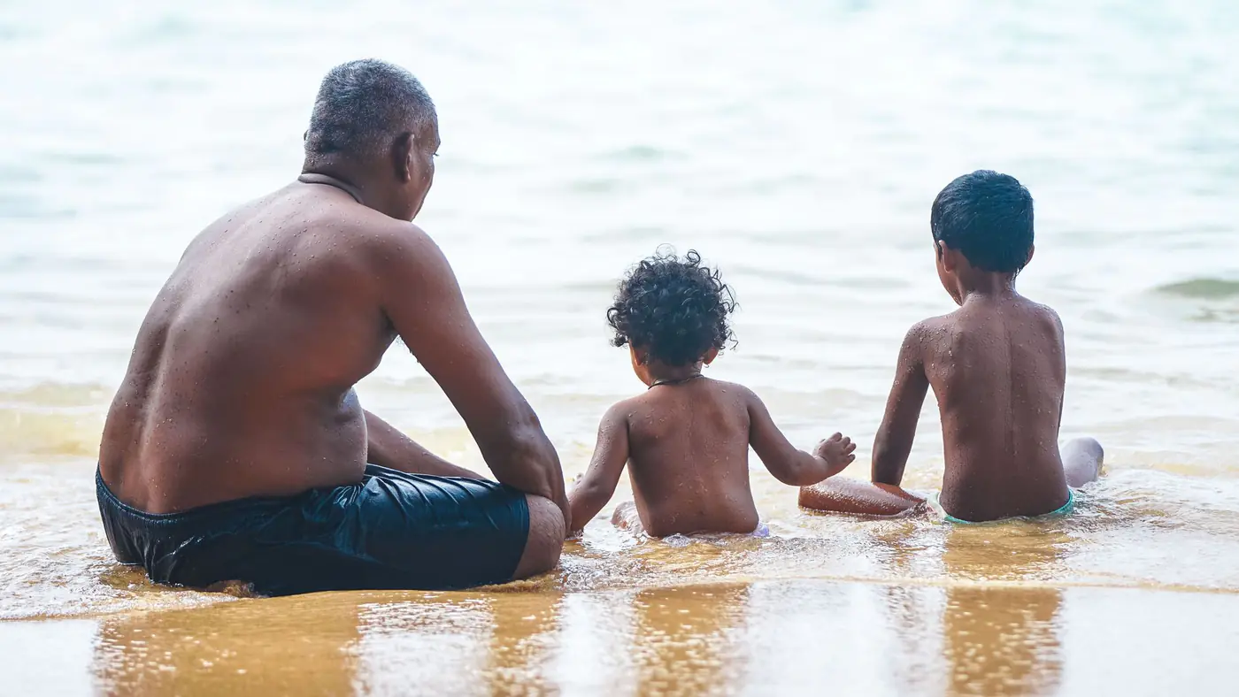 A father enjoys a bonding moment with his children at the serene beach shoreline.