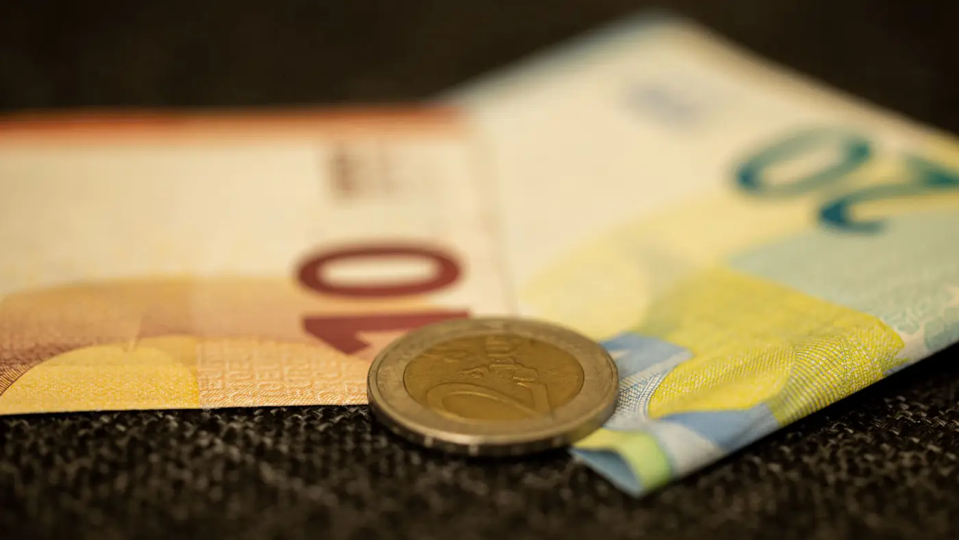 Detailed close-up of Euro banknotes and coin, showcasing European currency likeness.