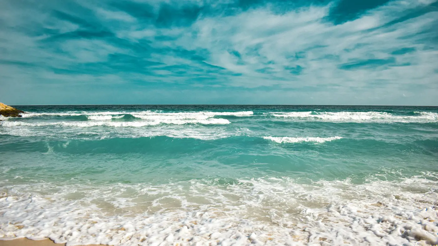 Idyllic beach with turquoise waves and clear sky. Perfect for travel themes.